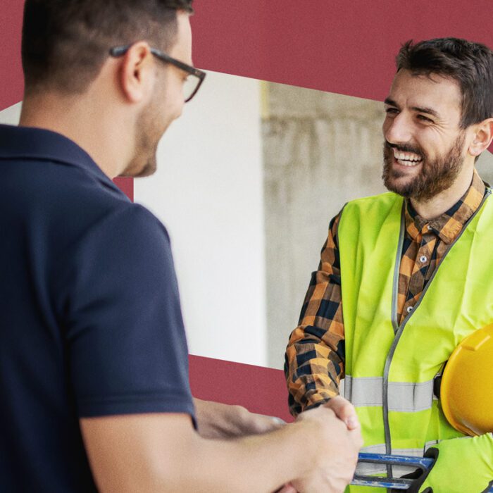 Two men shaking hands, one in a high-visibility vest and hard hat, both smiling