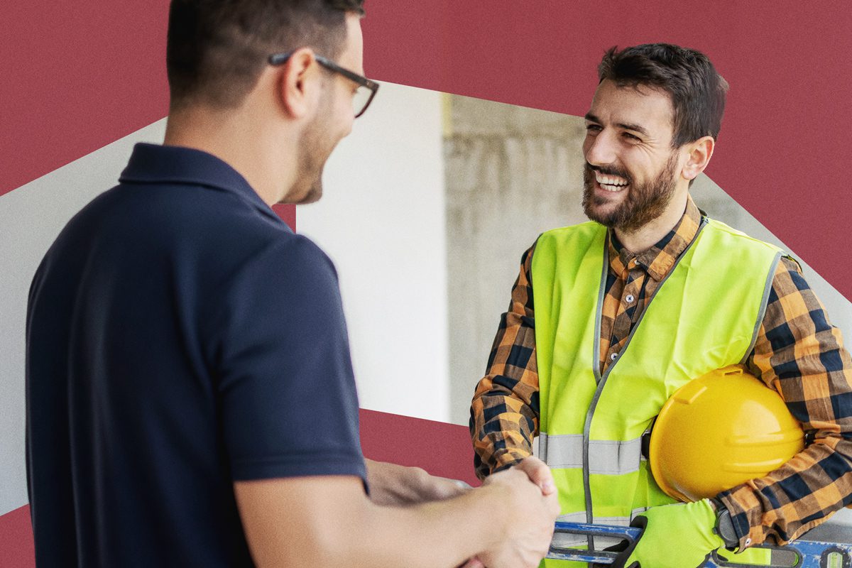 Two men shaking hands, one in a high-visibility vest and hard hat, both smiling