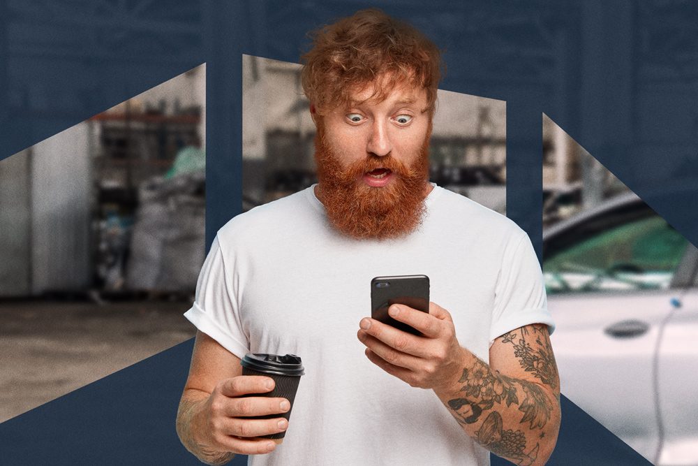 Man with red beard, eyes wide and mouth open, looking shocked at his phone while holding a coffee cup