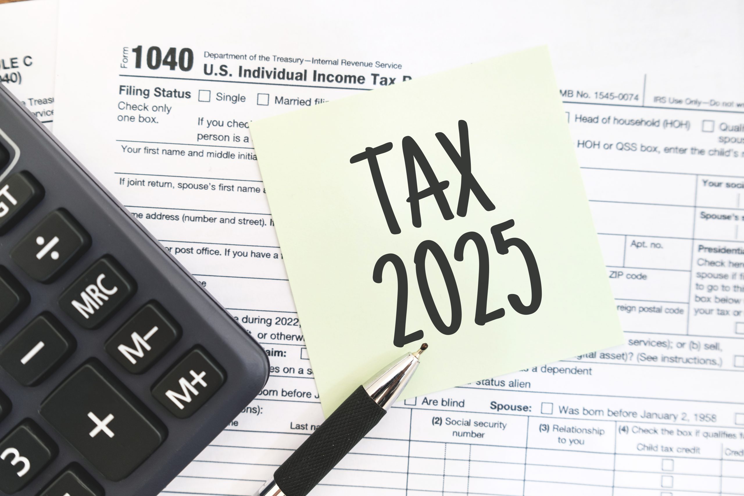 Text Tax 2025 on the note paper with calculator and taxes documents. Business and Annual tax concept.