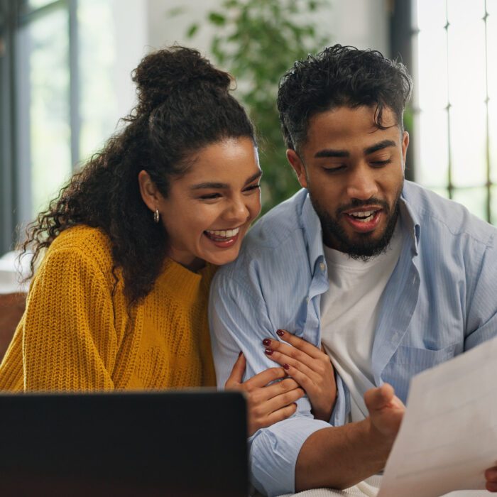 Happy, hug and couple with paperwork, home loan or excited for financial planning on website or app. Laughing, man and woman with document for mortgage, laptop and celebration with embrace in house