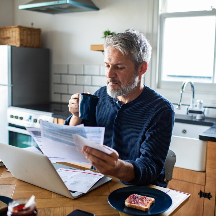 Mature man paying household bills at kitchen table