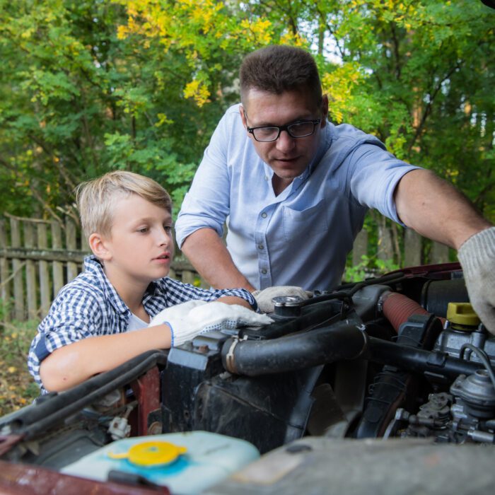 Father teaching his son how to check the oil on the family car.