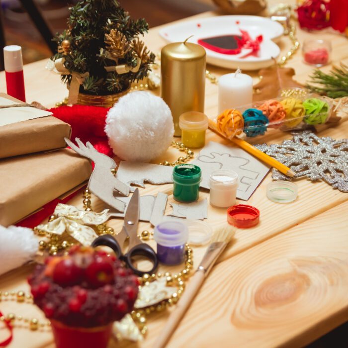 The girl at the table makes Christmas gifts. Hand made