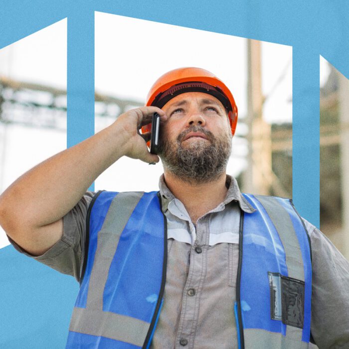 Man in a hard hat and safety vest talking on a cell phone, looking up