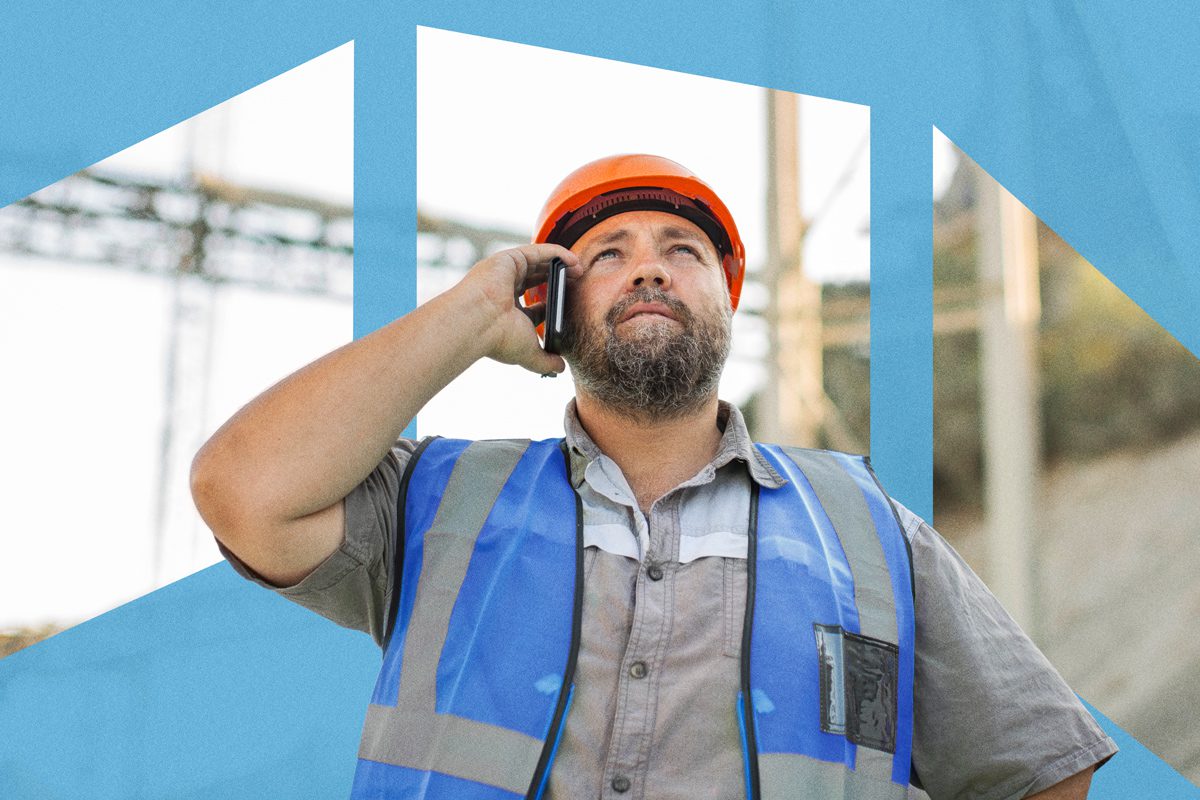 Man in a hard hat and safety vest talking on a cell phone, looking up