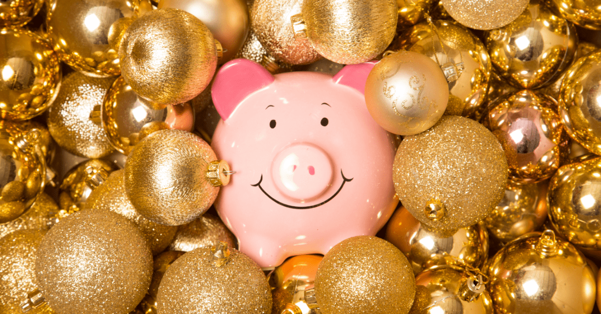 pink piggy bank nestled amongst gold christmas balls of various sizes and lusters