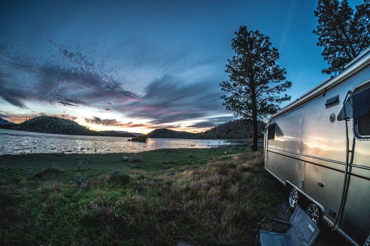 airstream on a lake with a beautiful sunset